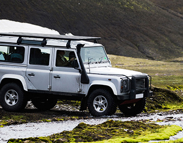 silver 4x4 driving through field