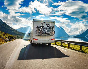 campervan with bikes attached to the back driving on country road